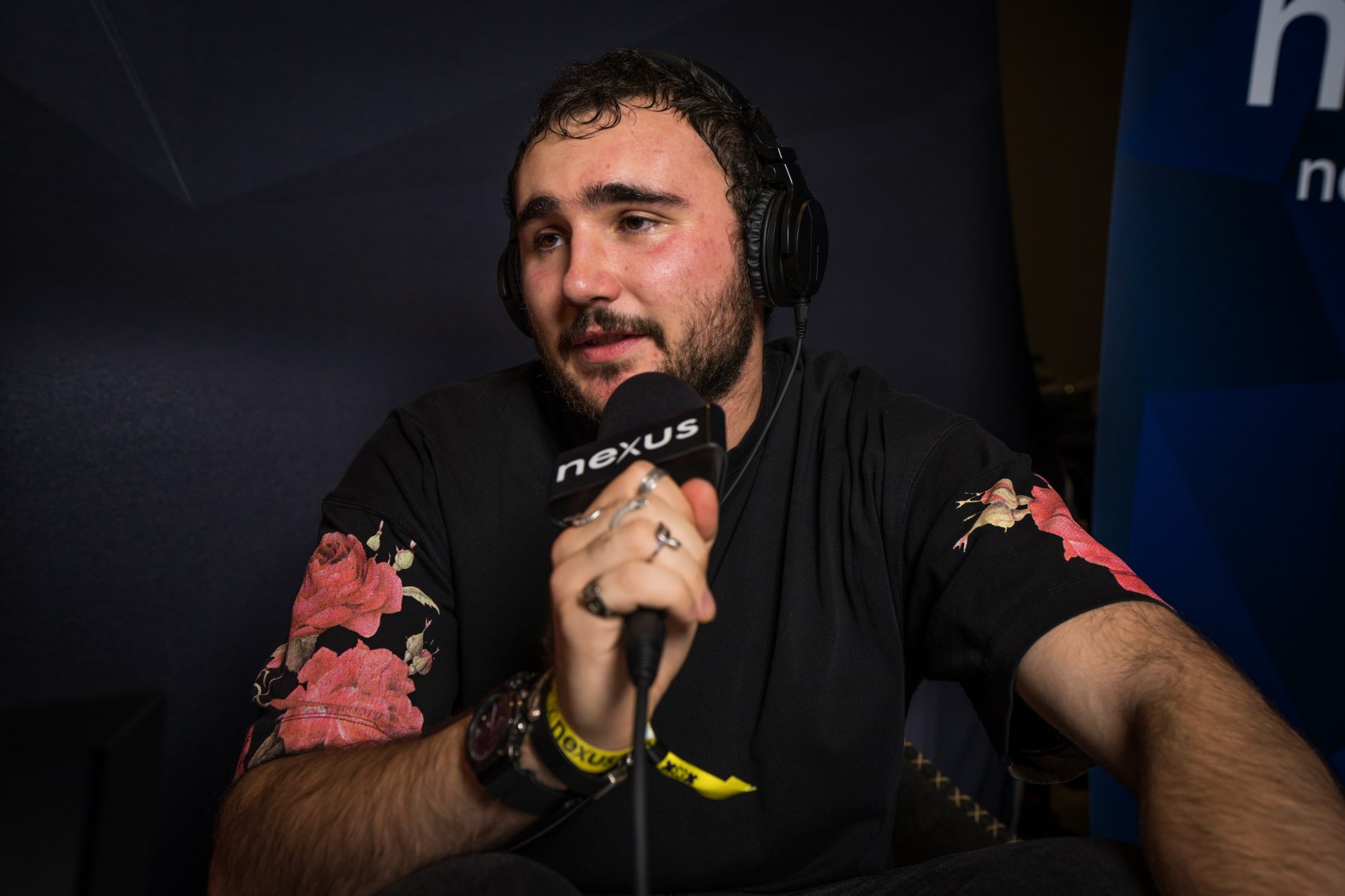 Person holding microphone, wearing floral shirt.